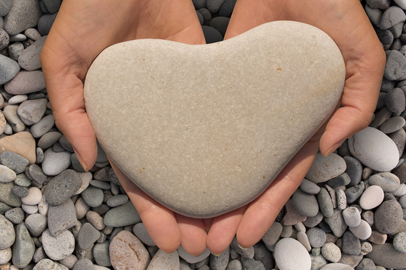Handing holding heart-shaped rock representing heart-felt connection, support and nurturing
